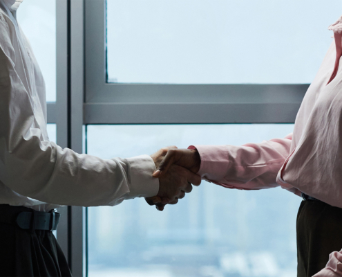 Header with colleagues shaking hands against panoramic