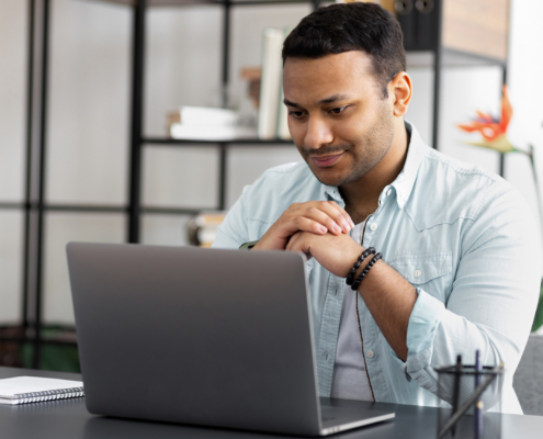 man looking at laptop screen sitting at home office