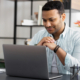 man looking at laptop screen sitting at home office