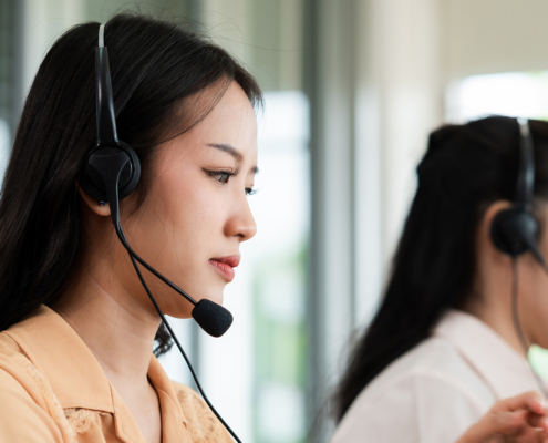 Team of call center staff in Asia wears headphones with a microphone